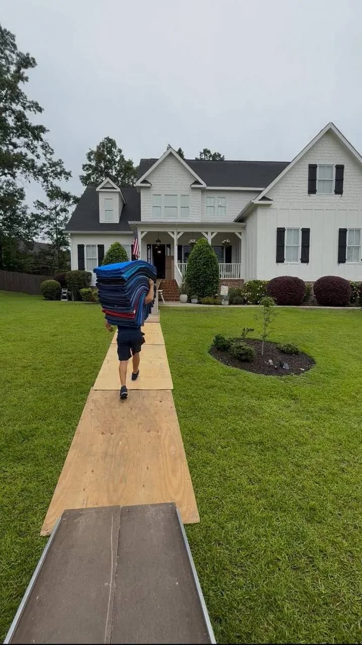 Mover carrying items across a lawn on a plank path