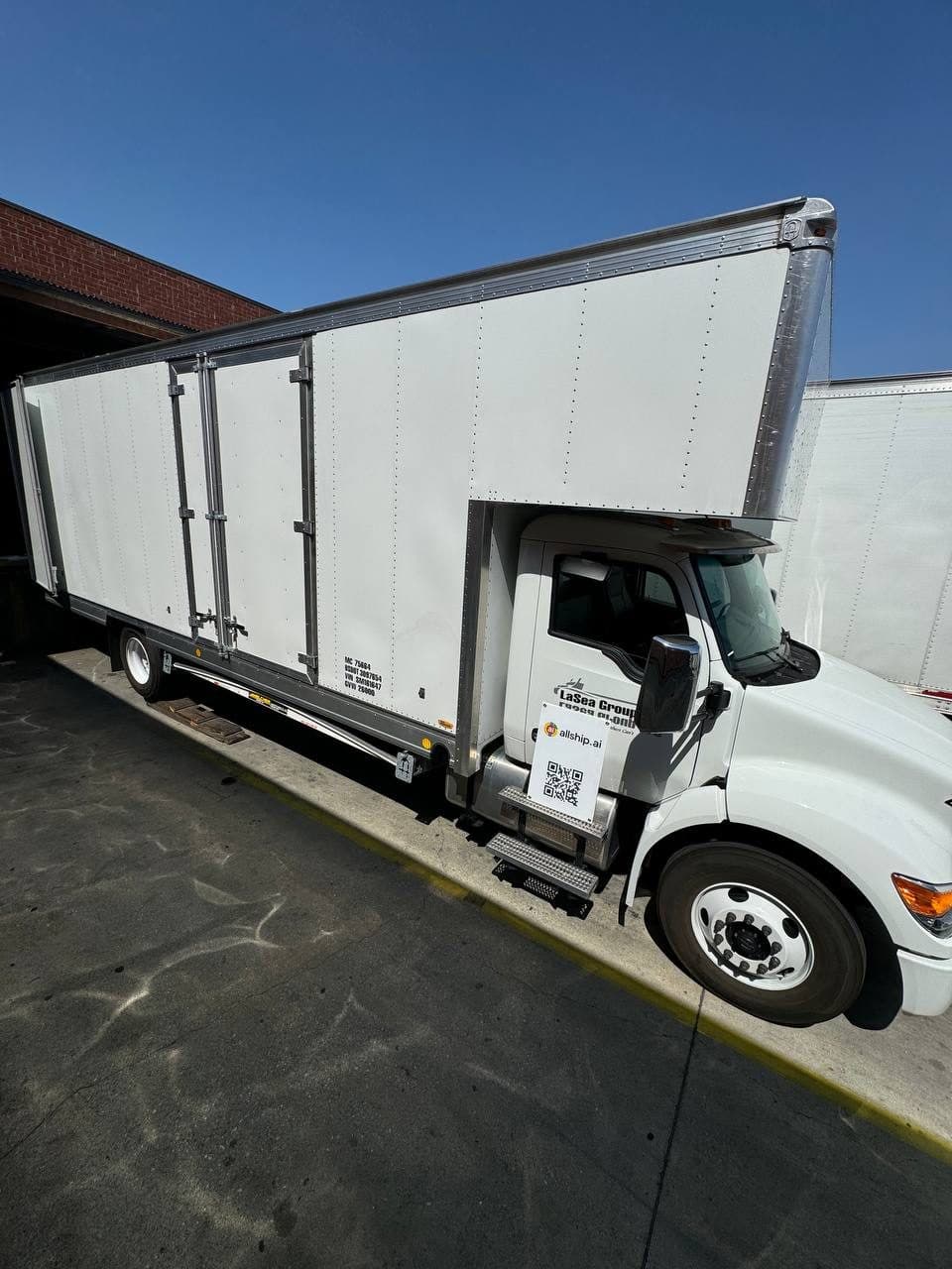 White box truck at a loading dock, seen from the side