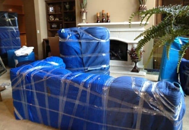 Sofa wrapped in moving blankets in a living room